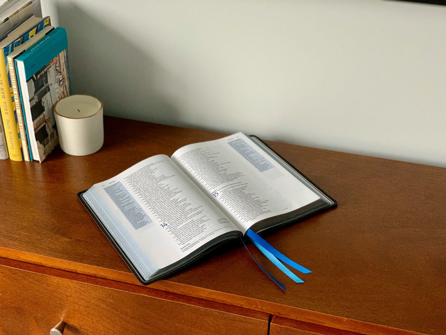 Open book with blue bookmarks rests on a wooden desk.